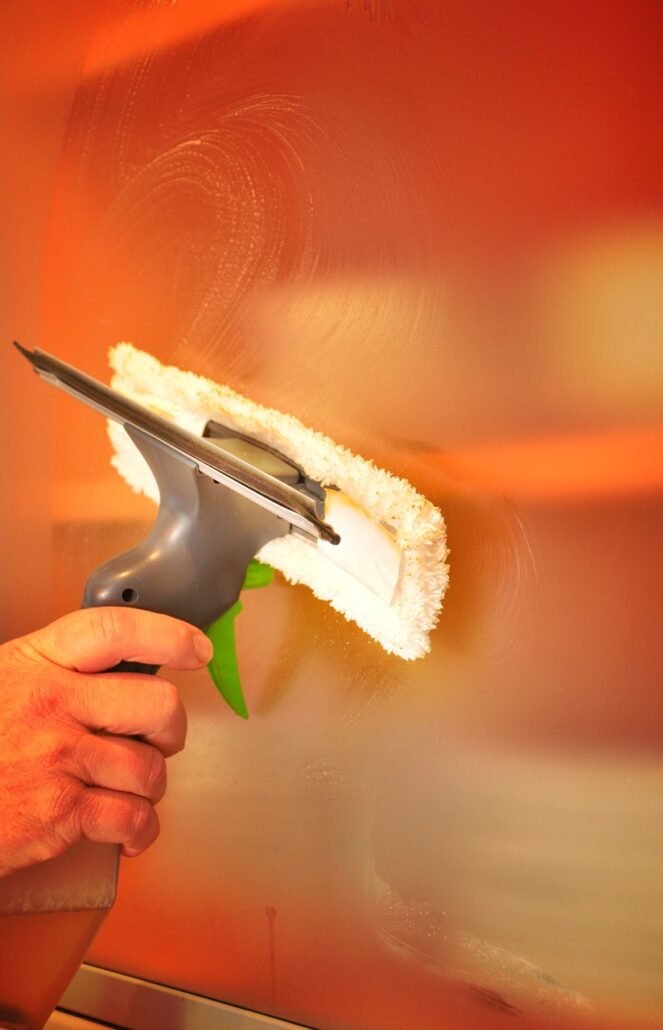 person cleaning window frame with sock on hand